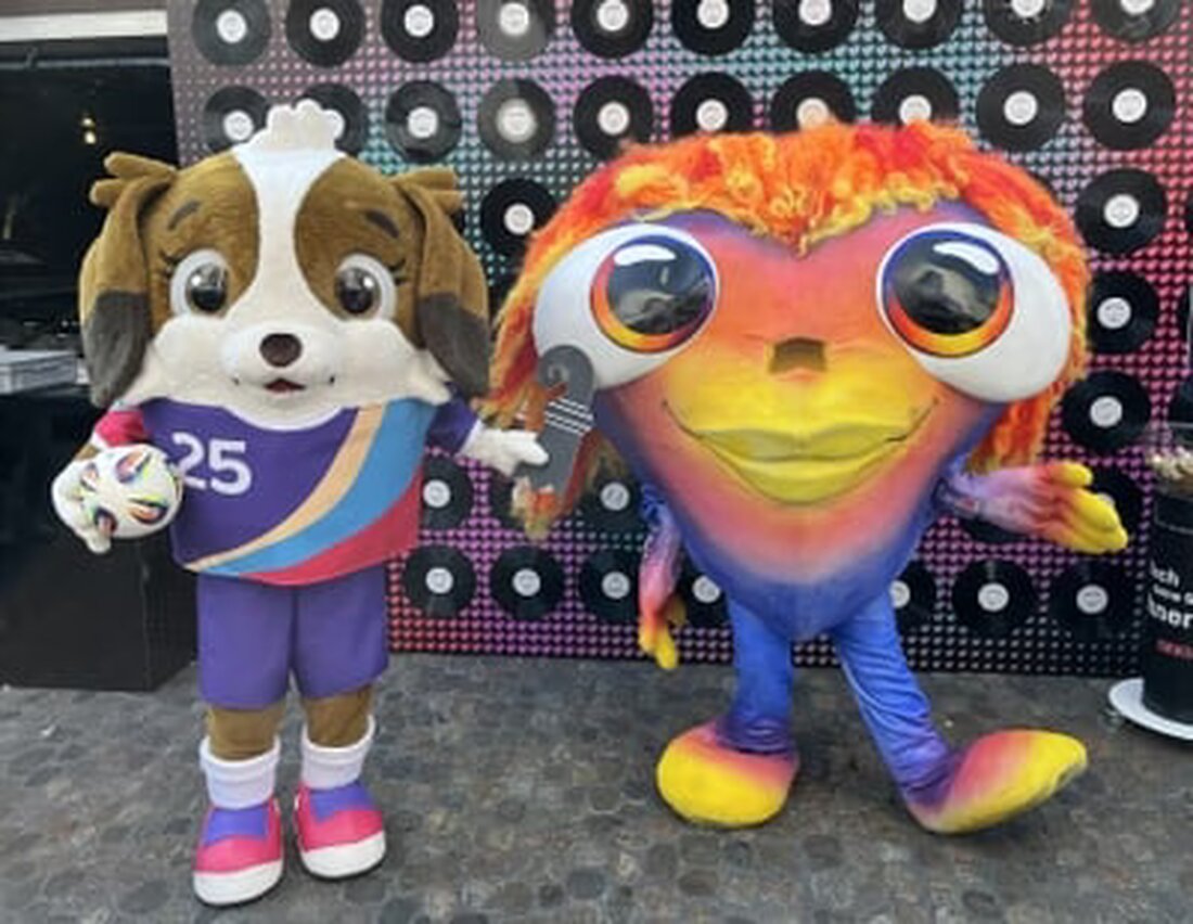 Nach dem Eurovision Song Contest 2025 übergibt Maskottchen Lumo symbolisch an Maddli vor der UEFA Women’s Euro in Basel.