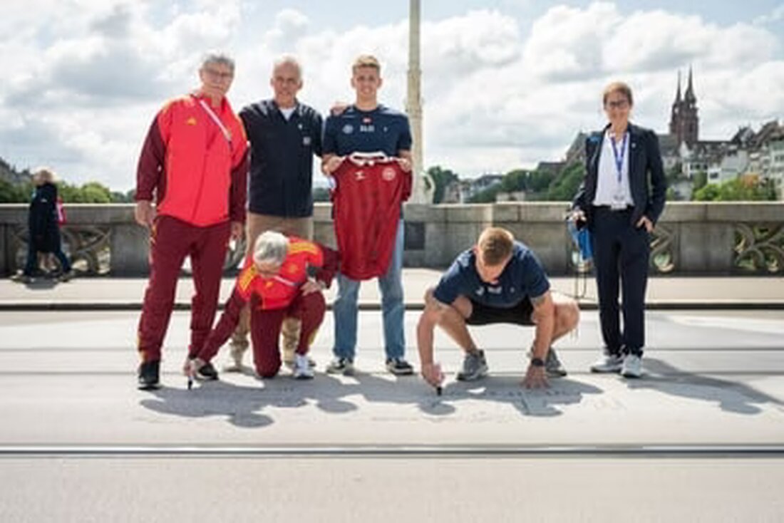 Vertreter der deutschen und dänischen Teams unterzeichnen heute einen überdimensionalen Fussball auf der Mittleren Brücke in Basel.